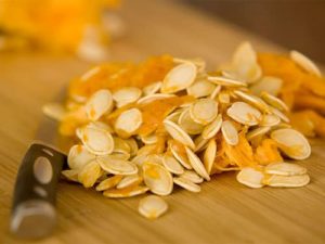 natural pumpkin seeds on a chopping baord before having their husks taken off